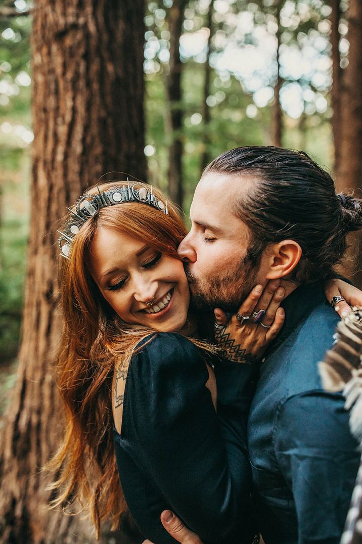 Man kisses his partner with red hair and silver crown for their engagement shoot