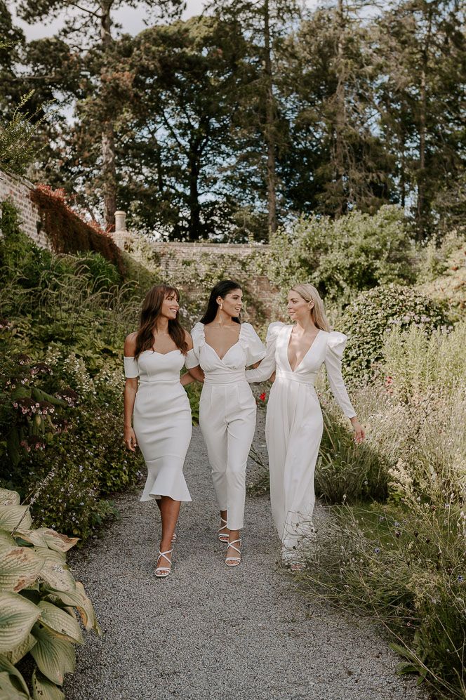 Bridal party wearing long and midi white bridesmaid dresses and neutral toned bouquets