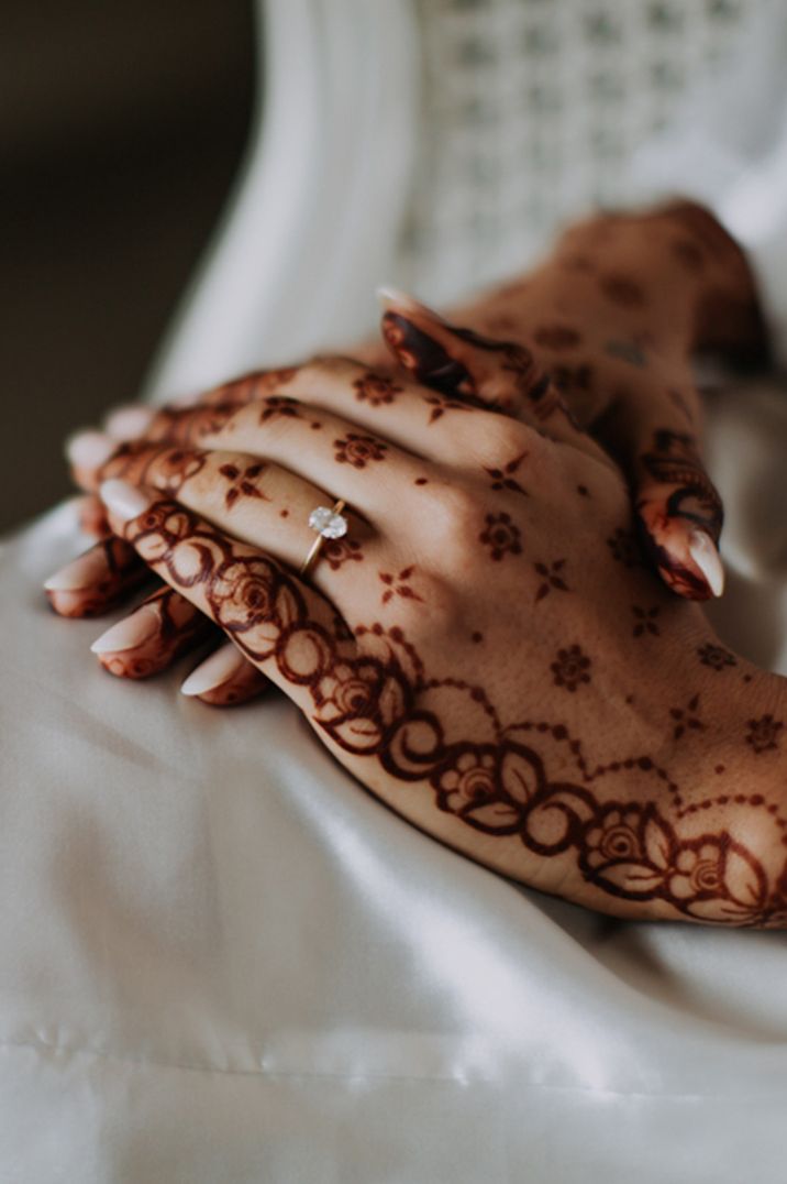 Indian bride with henna on her hands wearing a delicate diamond engagement ring