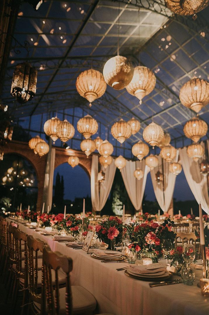 Marrakech wedding with gold wedding lanterns for destination wedding with pink flower arrangements and taper candles lining the tables