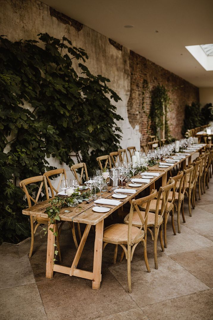 Simple wooden banquet table decorated with foliage and white plates at one of the most popular wedding venues of 2023 