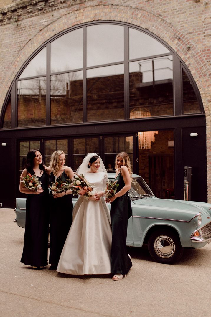 Wedding party pose in front of baby blue vintage car with dried flower wedding bouquets for LGBTQI+ wedding