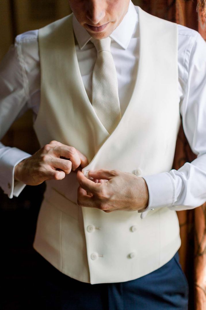 Groom getting ready in white blazer, white suit and white tie