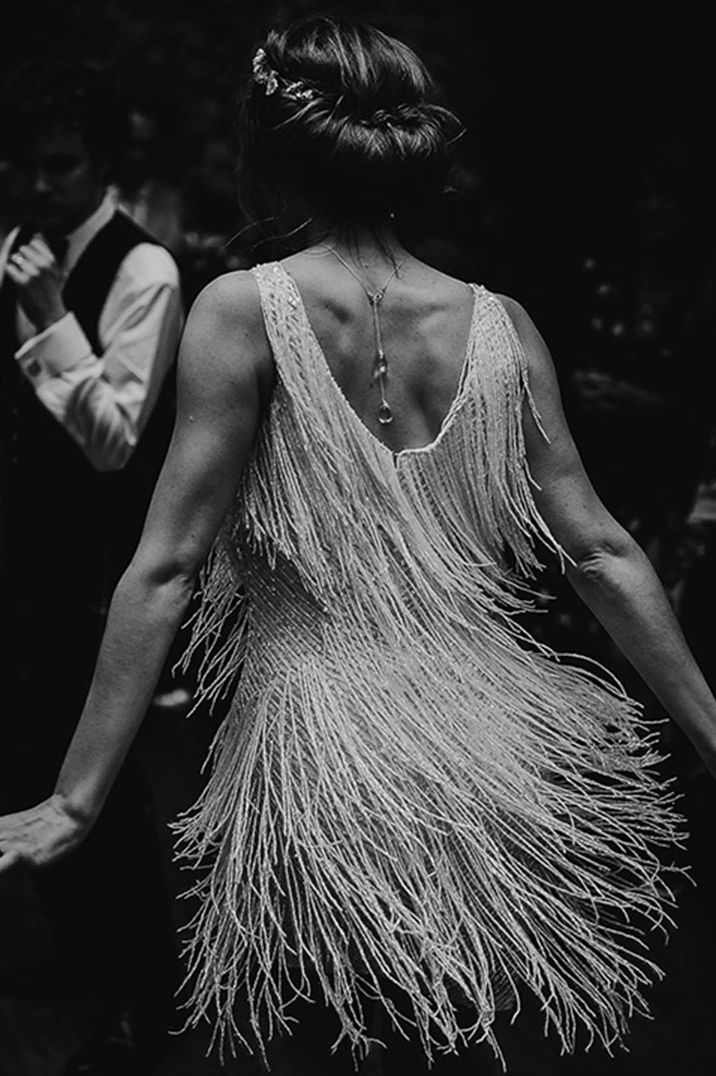 Bride dancing during the wedding reception in a short tassel Nadine Merabi white dress 