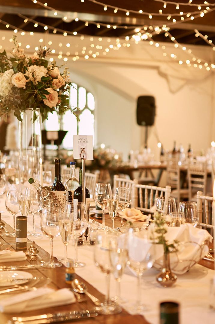 Classic rustic wedding tablescape with white table runners and rose and foliage centrepieces with fairy lights in Cluny Castle wedding reception room - wedding venues Scotland