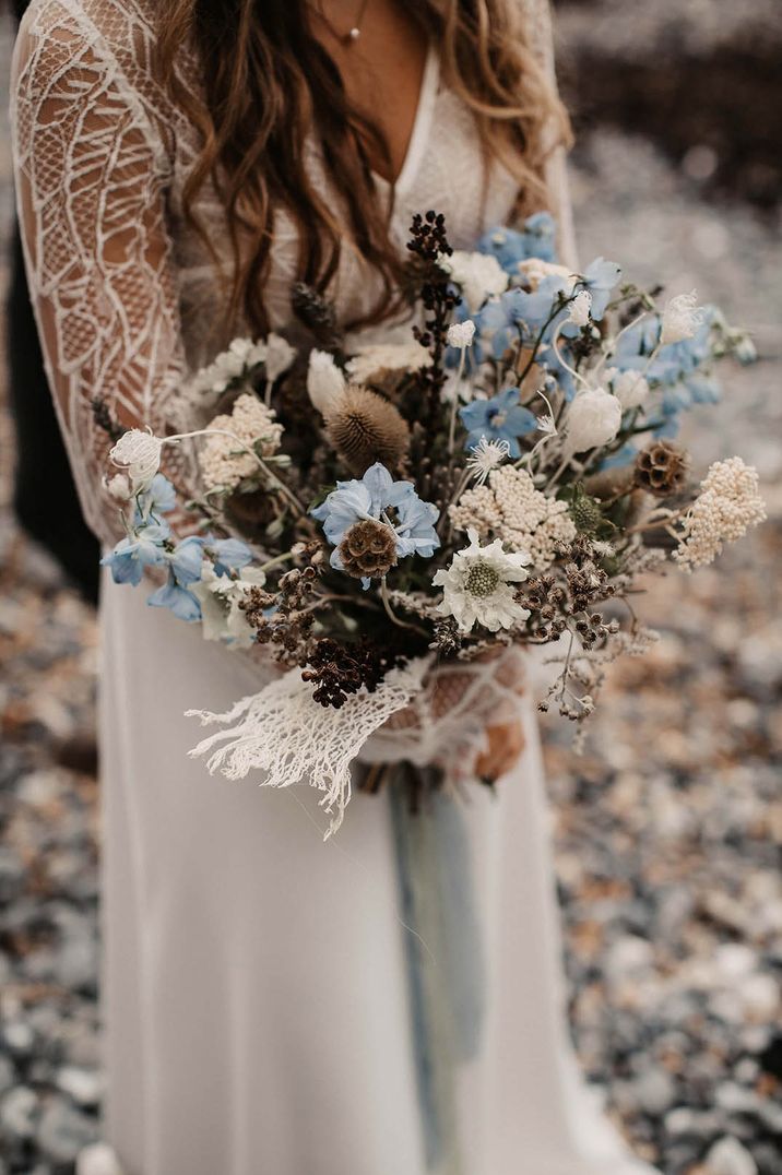 Coastal wedding with bride carrying a pastel blue flower wedding bouquet with dried flowers or rustic look 