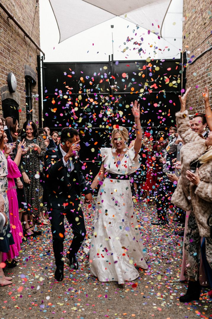 Colourful confetti moment at The Loft Studios London with bride in a ruffle sleeve wedding dress and groom in a wool suit 