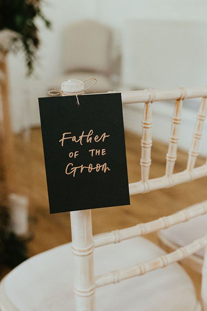 Black and gold wedding seat reserved sign at the ceremony of the father of the groom for autumnal wedding 