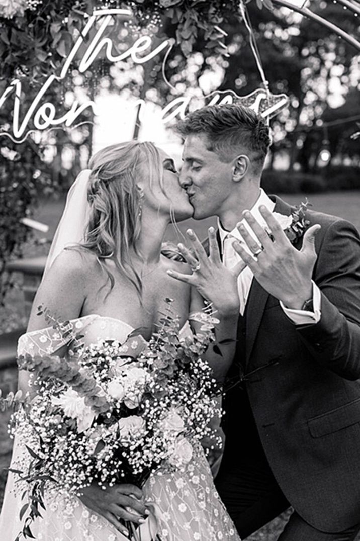 The bride and groom share a kiss as they show off their diamond engagement rings 