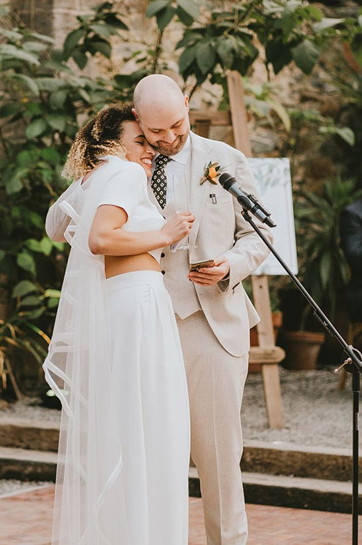 The bride rests her head on the groom's shoulder as they read out their joint wedding speech 