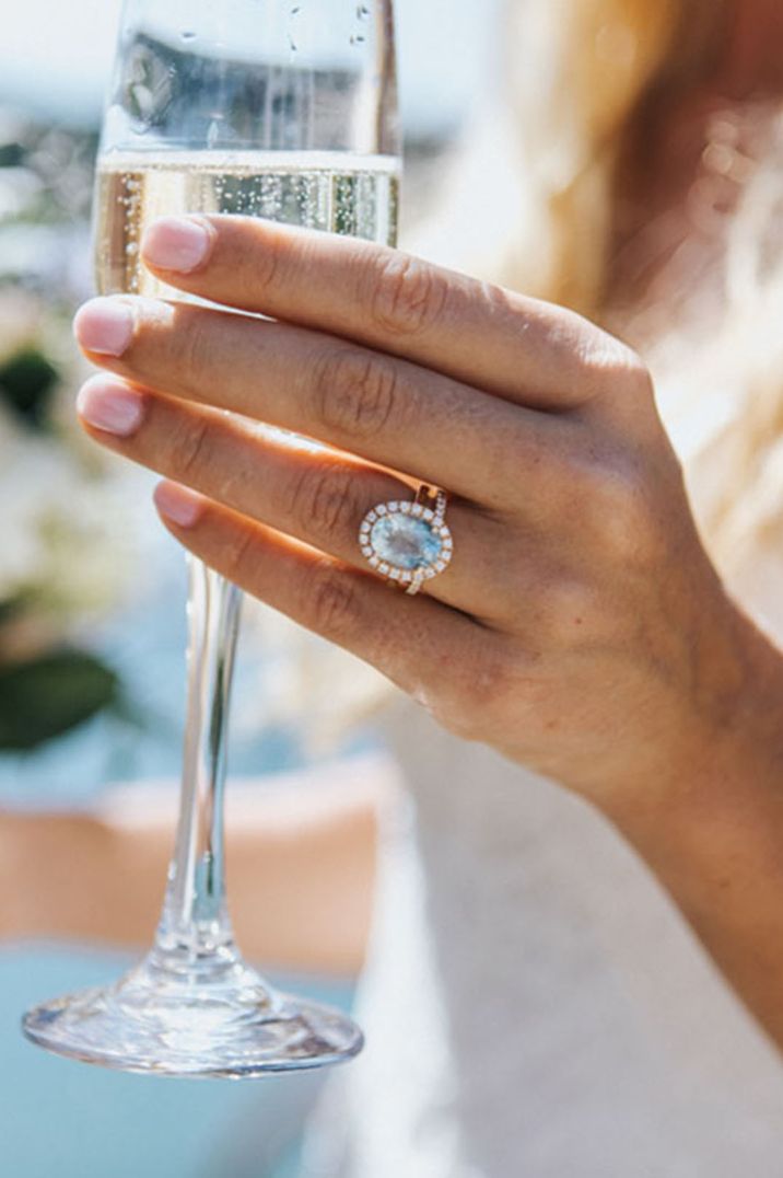 Bride with large diamond engagement ring drinking glass of champagne 