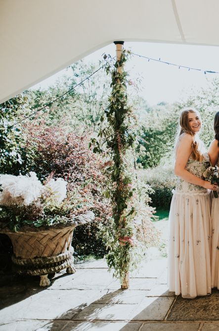 Bridal party portrait under a stretch tent with Bride in a lace wedding dress and bridesmaids in embroidered halter neck dresses 