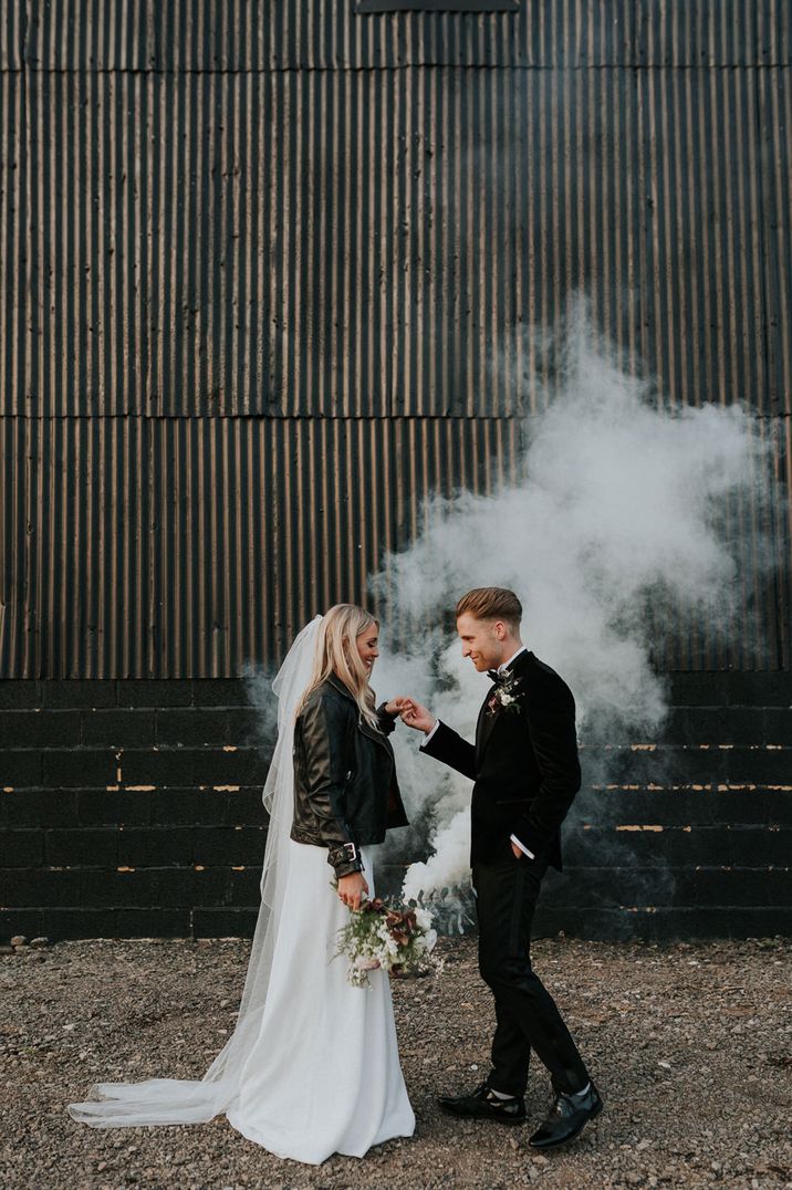 White smoke bomb wedding portrait with the bride in a personalised leather jacket and the groom in a tuxedo 