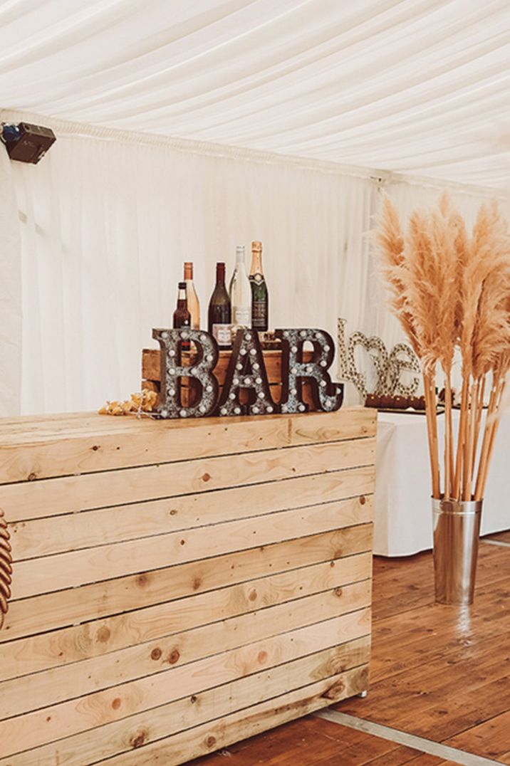 Marquee wedding bar design with rustic wedding signage and wooden crate 