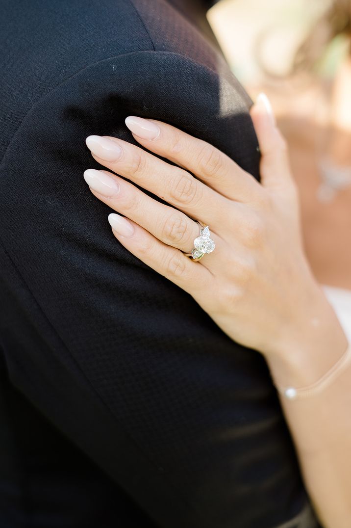 Bride with almond shaped wedding nails and large oval diamond engagement ring with trinity stones 