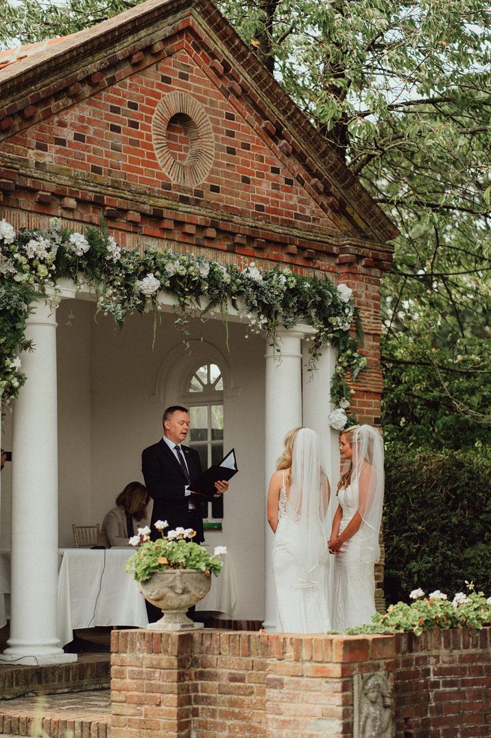 Outdoor wedding ceremony at Micklefield Hall with two brides in lace wedding dresses 