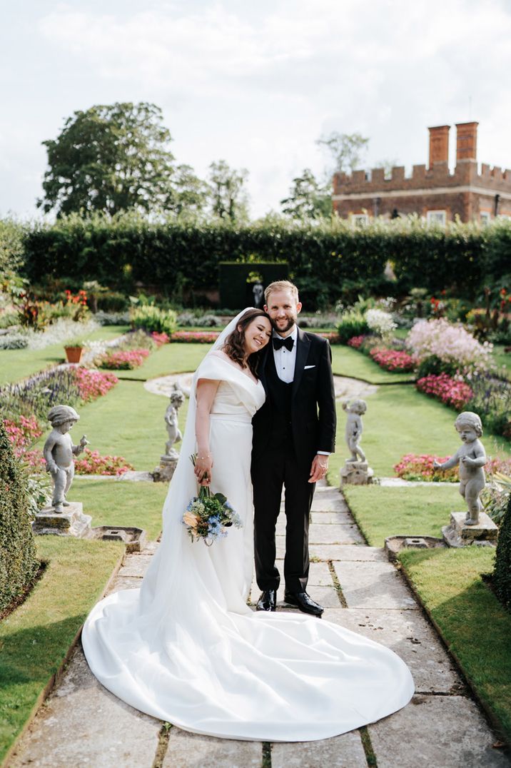 Bride in an off the shoulder wedding dress and groom in a tuxedo at luxury Hampton Court Palace wedding 