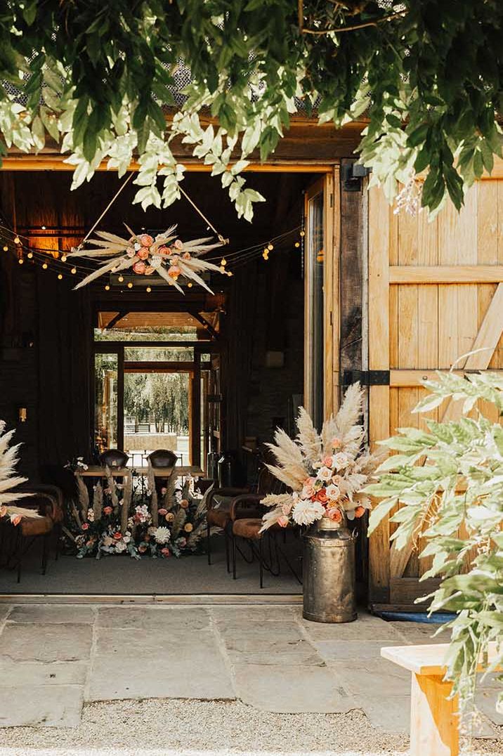 Open wooden barn doors and earthy themed decorations at barn wedding venue