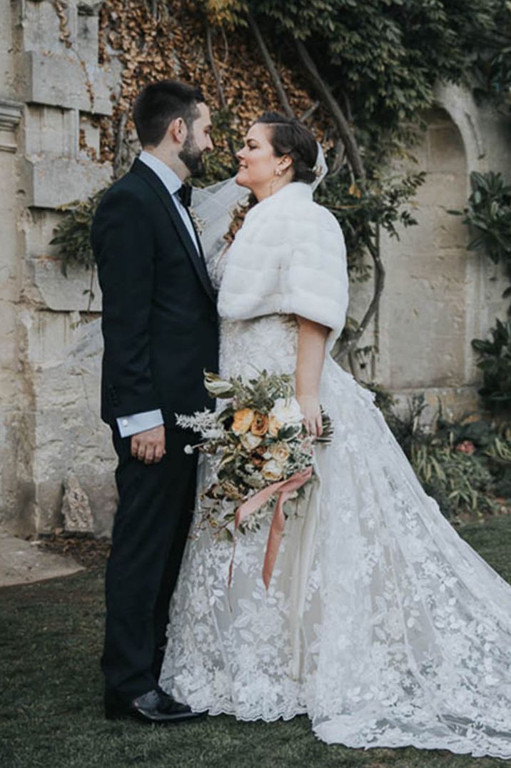 60k wedding in winter with the bride wearing a fur cover up posing with the groom in a black tuxedo for their country house wedding 