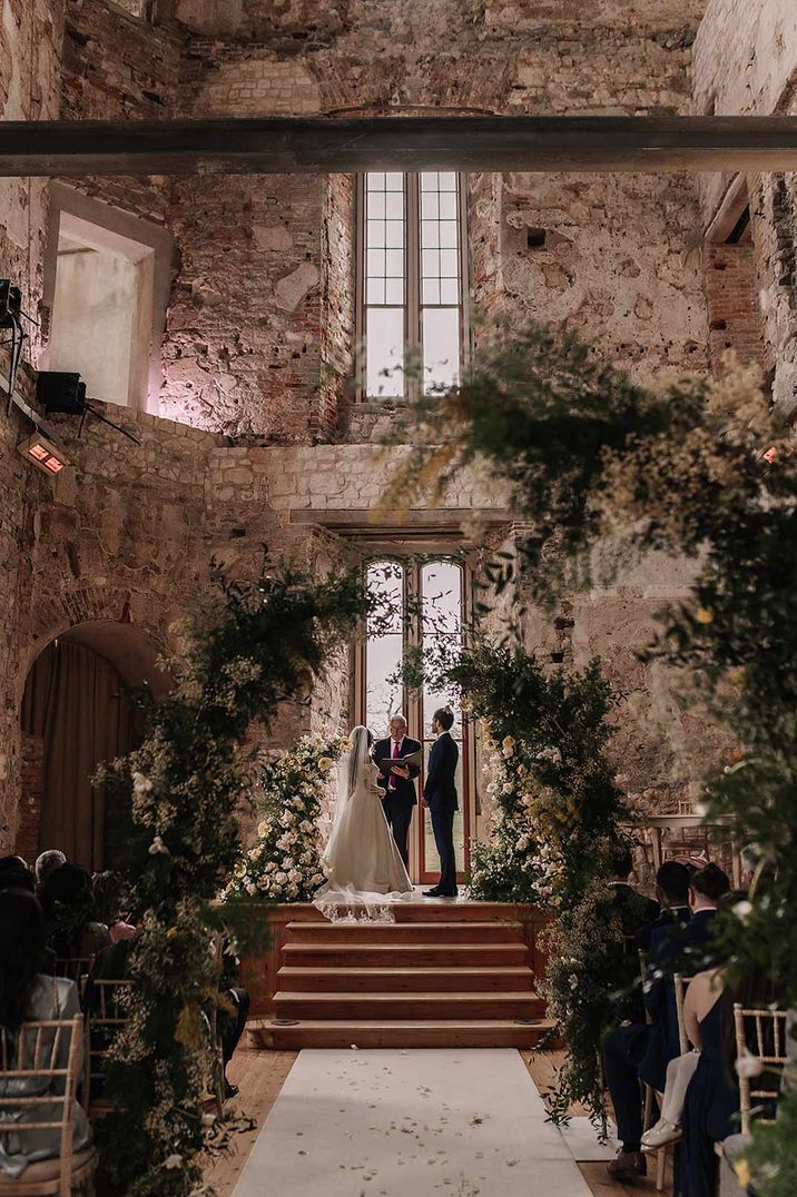 Bride and groom at the end of the alter with large suspended foliage decorations - last minute wedding preparations