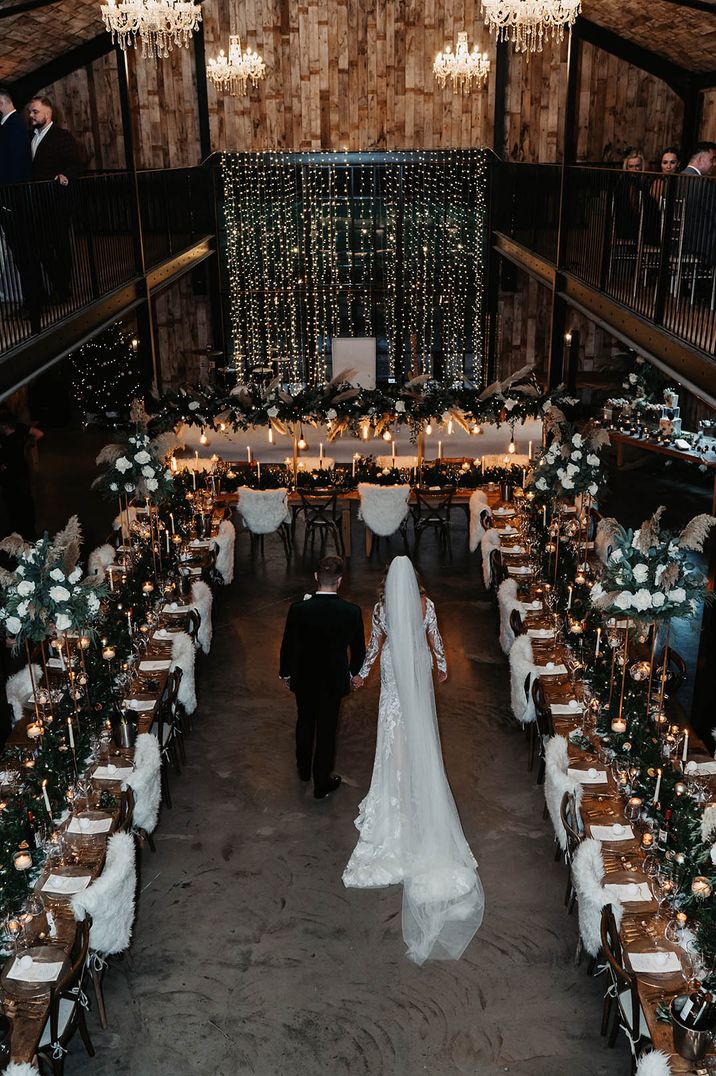 The bride and groom walk around Hidden River Cabins with long banquet tables and magical winter wedding decor 