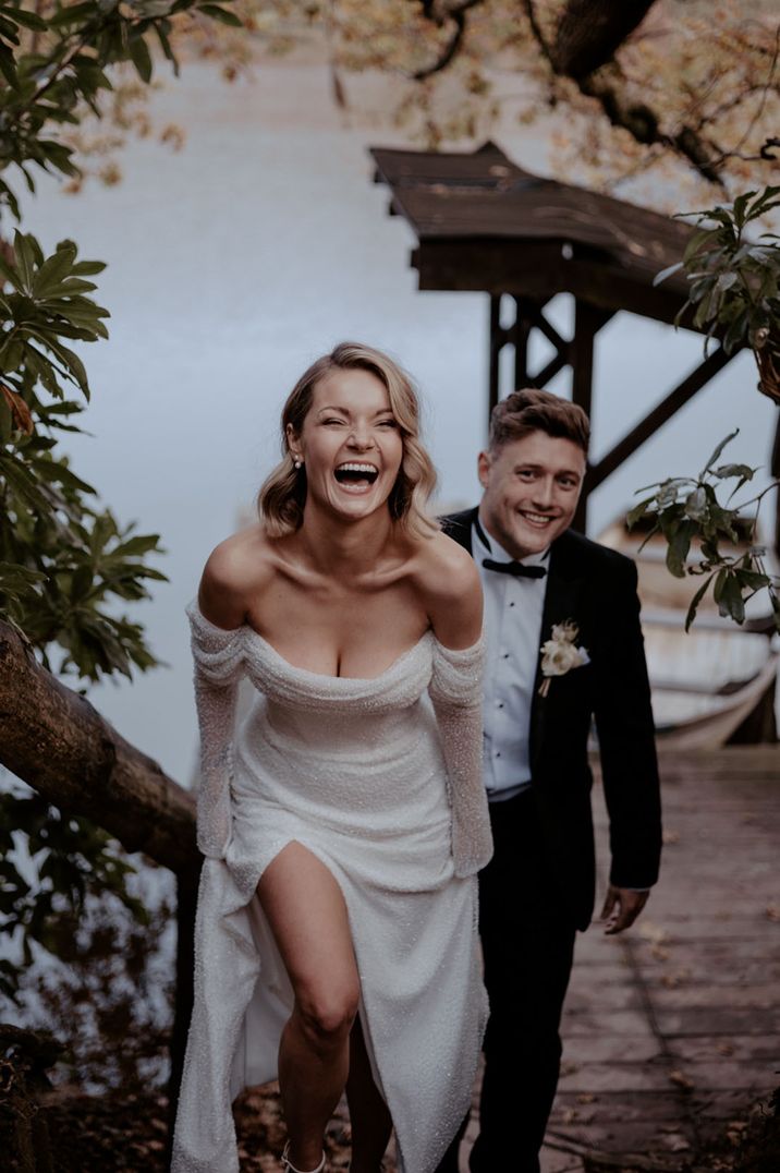 Bride wearing an off the shoulder wedding dress laughing with groom at their winter wedding 