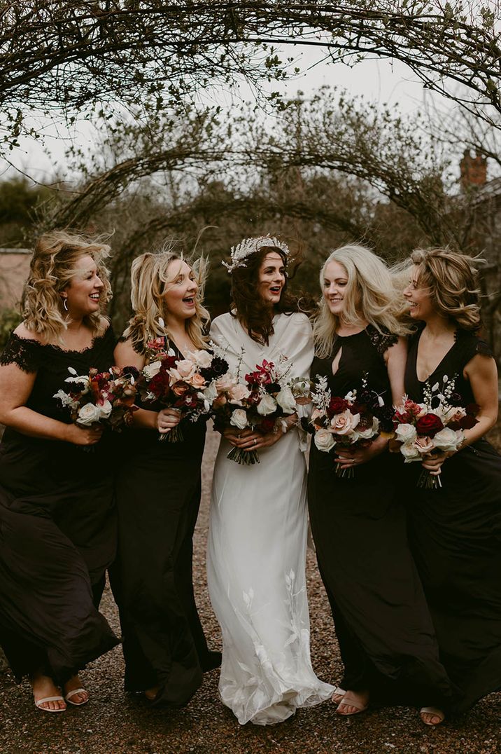 Bridal party wearing black bridesmaid dresses with the bride in a white wedding dress on windy wedding day 