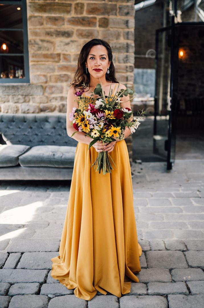 Bride in mustard yellow wedding dress holding sunflower wedding bouquet 