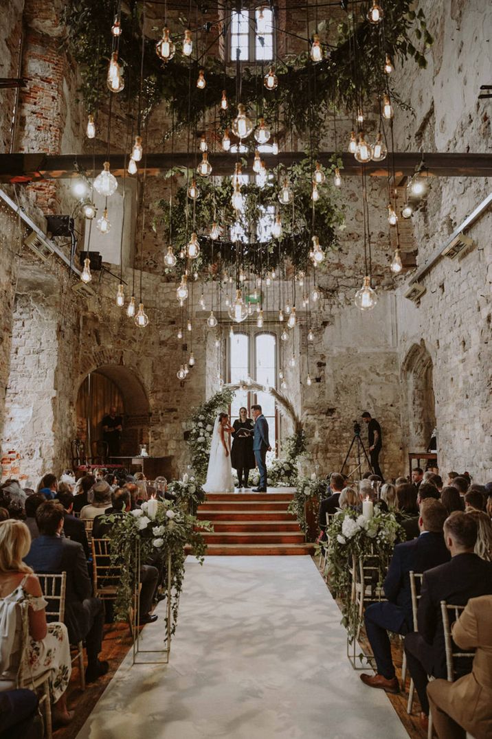 Lulworth castle wedding ceremony with pampas grass and foliage moon gate and Edison bulb light installation