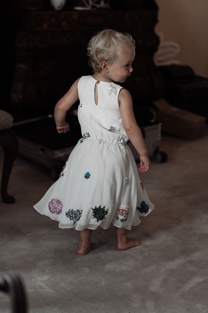 Flower girl in white dress with flower design along the bottom