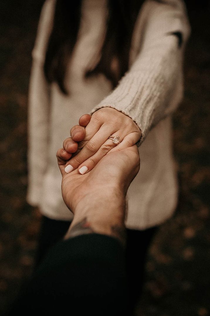 Woman shows off her engagement ring with white painted finger nails 