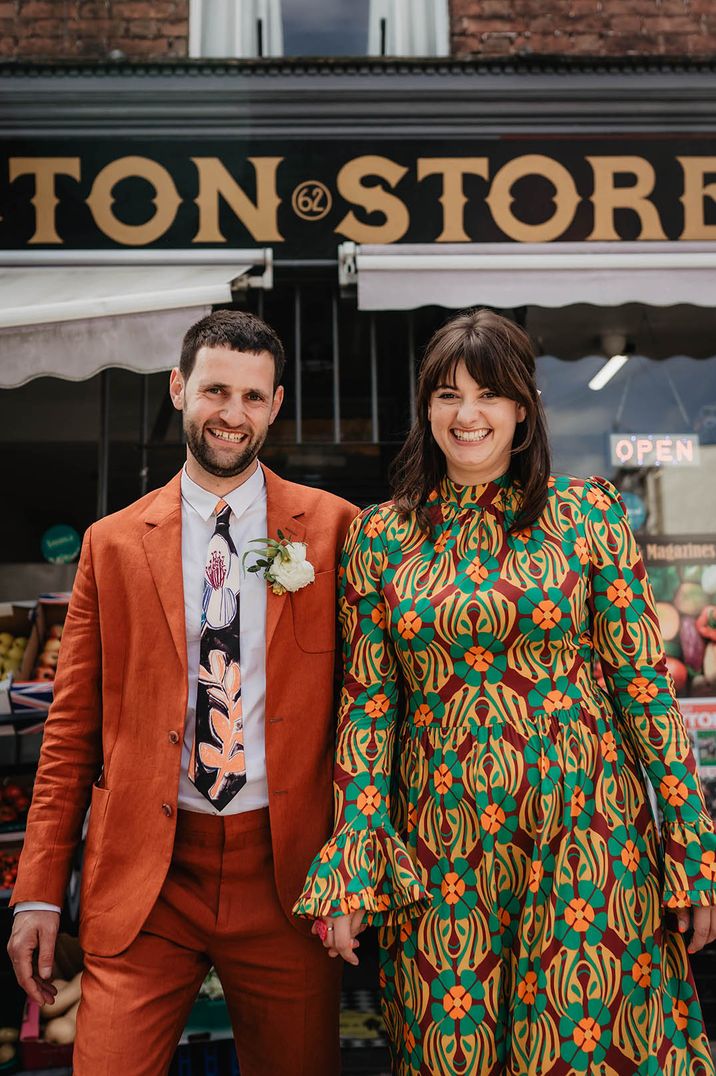 Groom in orange suit and funky with bride in retro green patterned wedding dress 