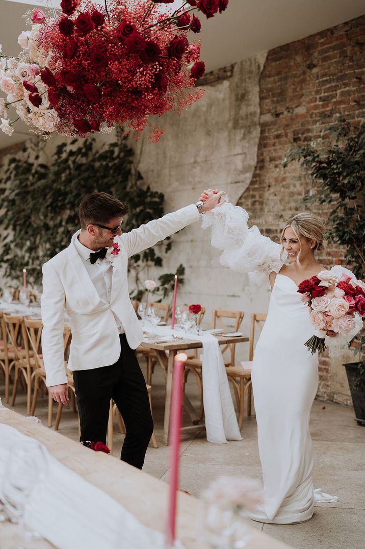 Bride in pearl puff sleeve wedding dress dancing with groom in white tuxedo at Middleton Lodge Estate wedding venue 