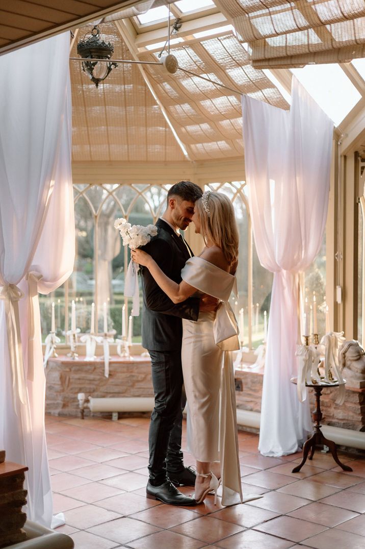 The bride and groom pose for their couple portrait in the conservatory at Dewsall Court 