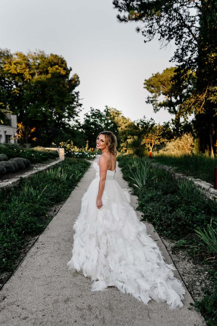 Bride in strapless feather wedding dress with her hair in a messy updo 