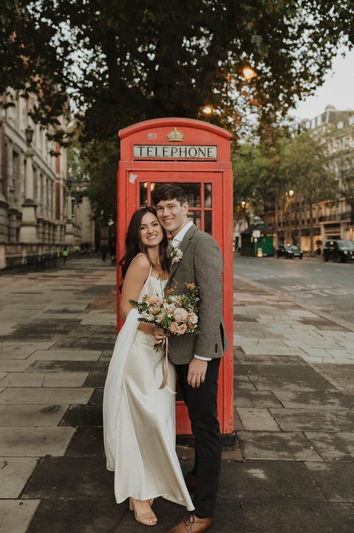 Groom in grey tweed suit with the bride in a classic style satin wedding dress at London city wedding