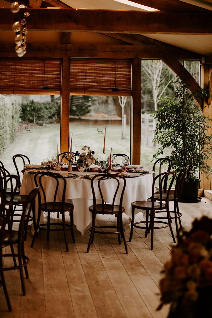 Round wedding tables decorated with white table cloths, neutral taper candles and black accents 