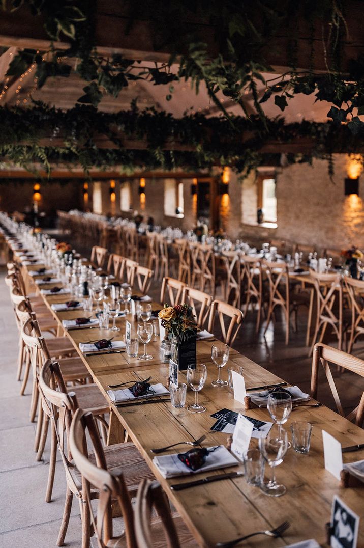 Long wooden tables decorated with natural decor and foliage at barn wedding venue 