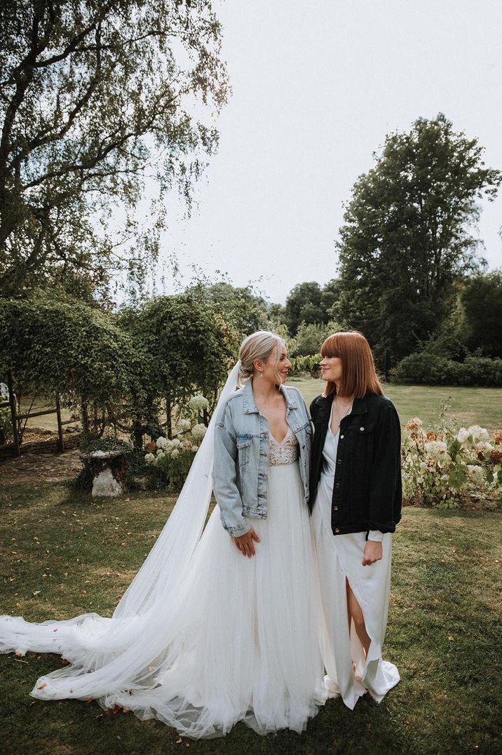 Lesbian wedding with two brides in a princess wedding dress and blue denim jacket and wrap wedding dress with black denim jacket 