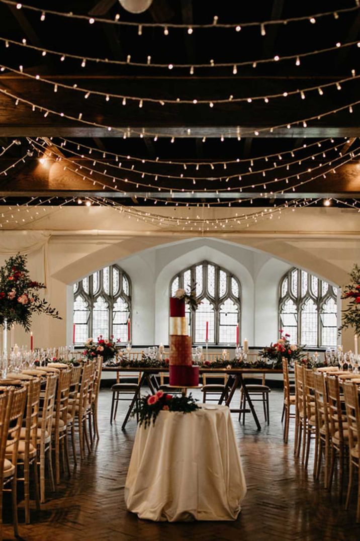 Reception room of Cluny Castle wedding venue Scotland - fairy lights hanging from the ceiling with classic tablescapes and large floral arrangements