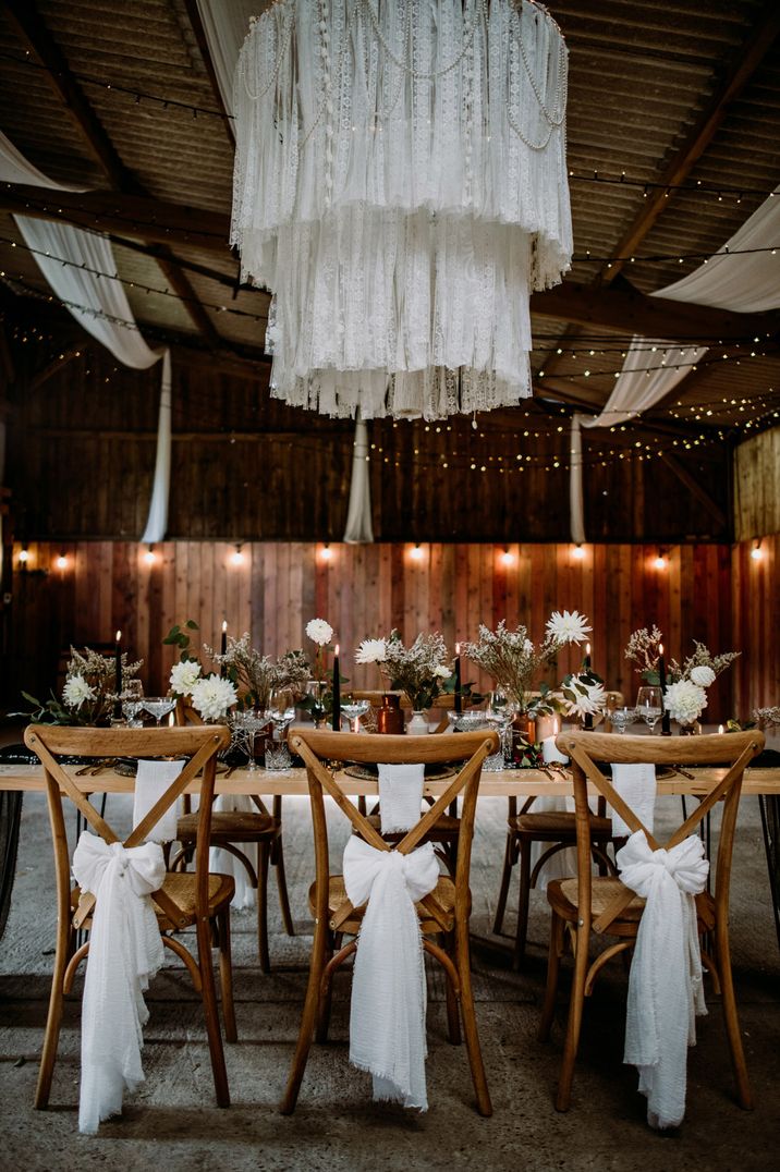 White bow chair back decorations for rustic barn wedding with wooden chairs and tables 