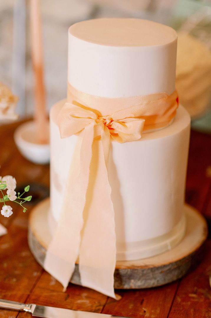 Two tier white iced wedding cake with pink wedding bow decoration 