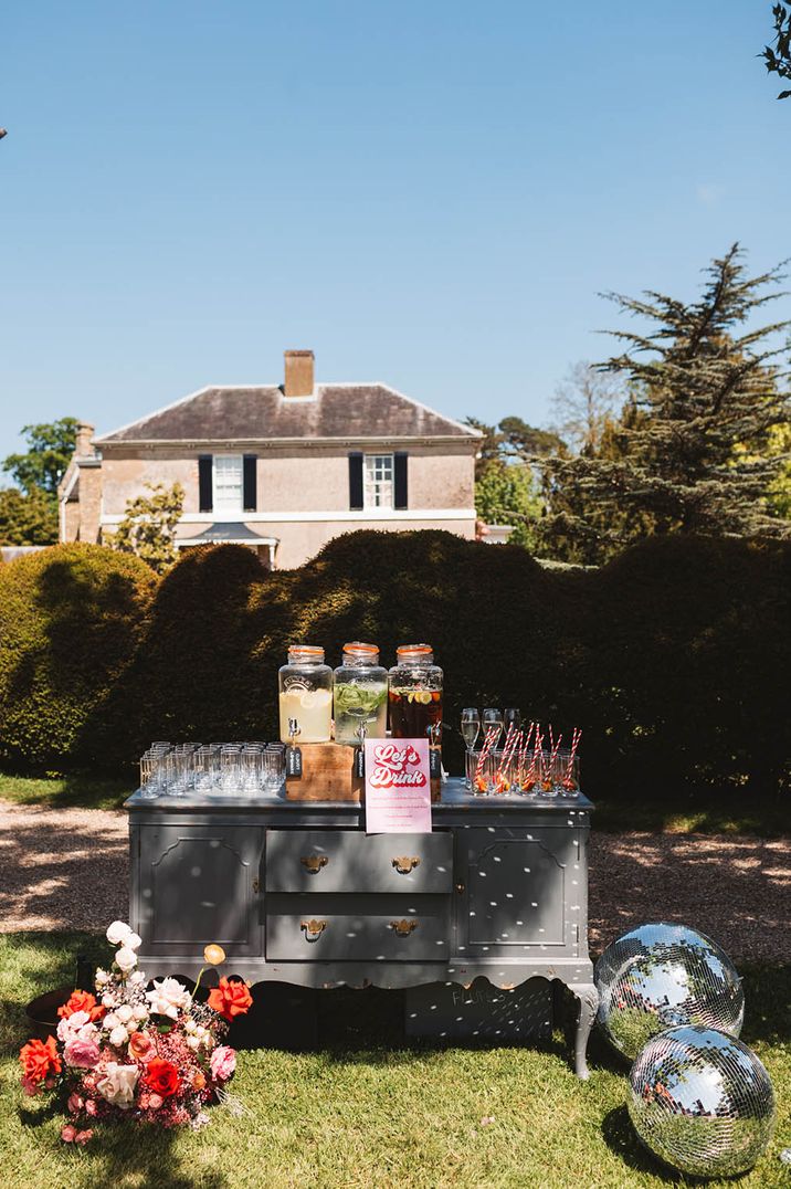 Outdoor summer wedding with different flavour drink dispensers with glasses and straws 