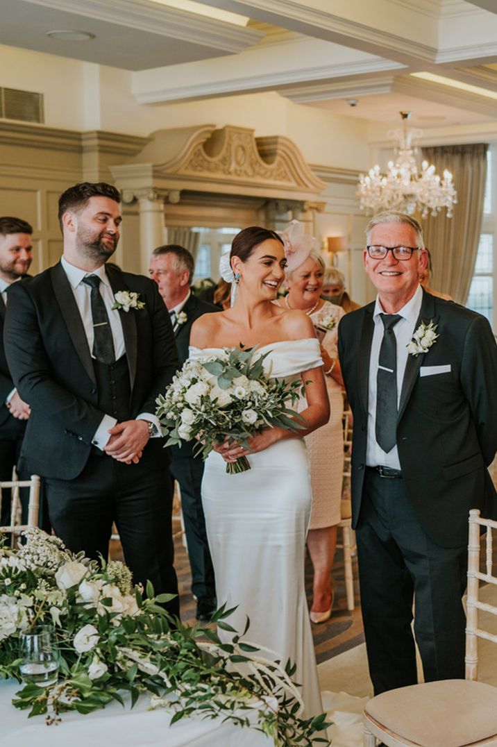 Father of the bride walks the bride to the groom at the altar for their wedding ceremony at hotel wedding venue in Northern Ireland 