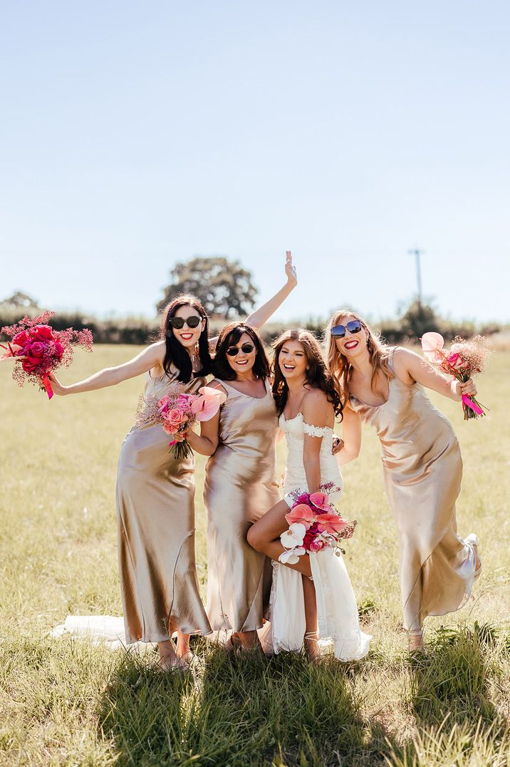 Bridal party in gold bridesmaid dresses with hot pink bouquets 