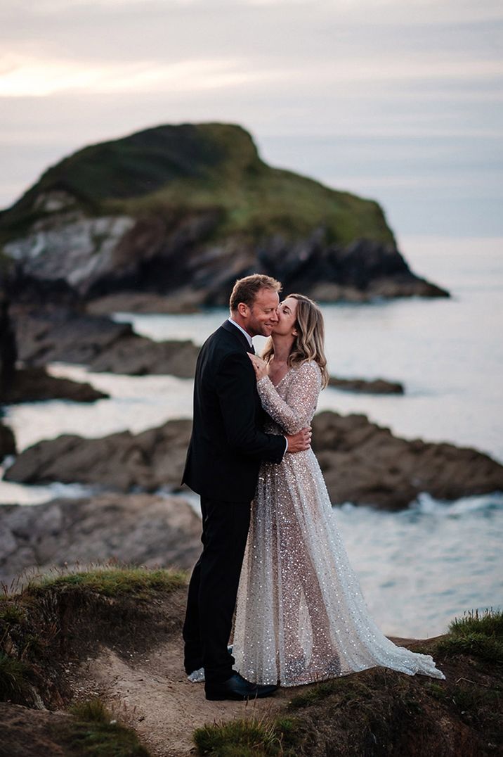 Bride in sparkly long sleeve sequin wedding dress embracing the groom for couple portrait 