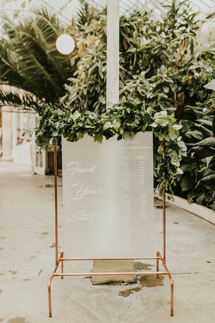 Frosted table plan on a copper Fram with decorative foliage 