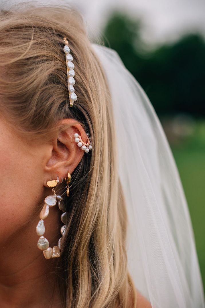 Bride wears bridal ear curated complete with statement hoop earring and pearl earring to cartilage   