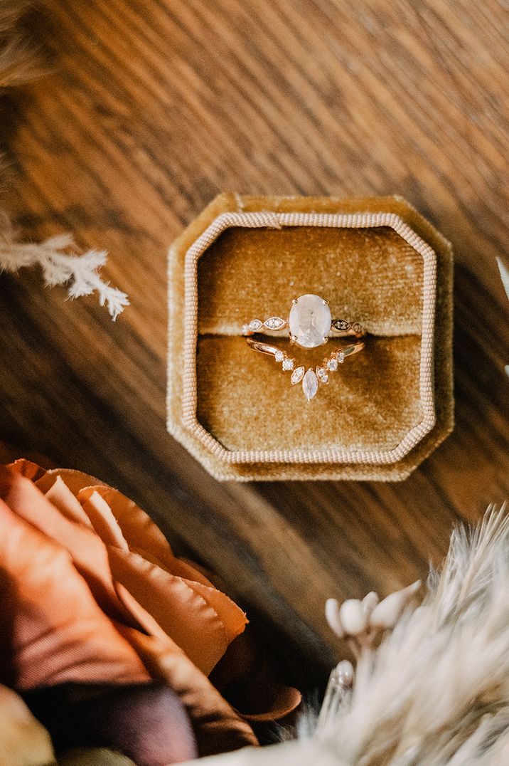 Mustard yellow velvet ring box with wishbone shaped wedding band and oval diamond engagement ring 