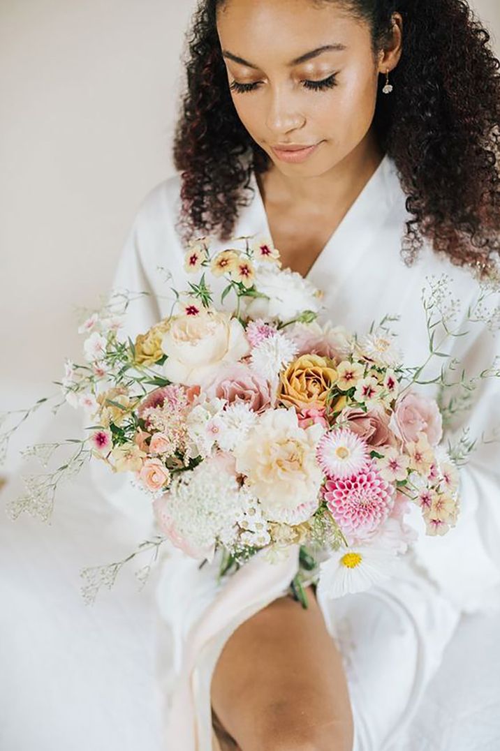 bride with afro curly hair on wedding day, holding her bouquet